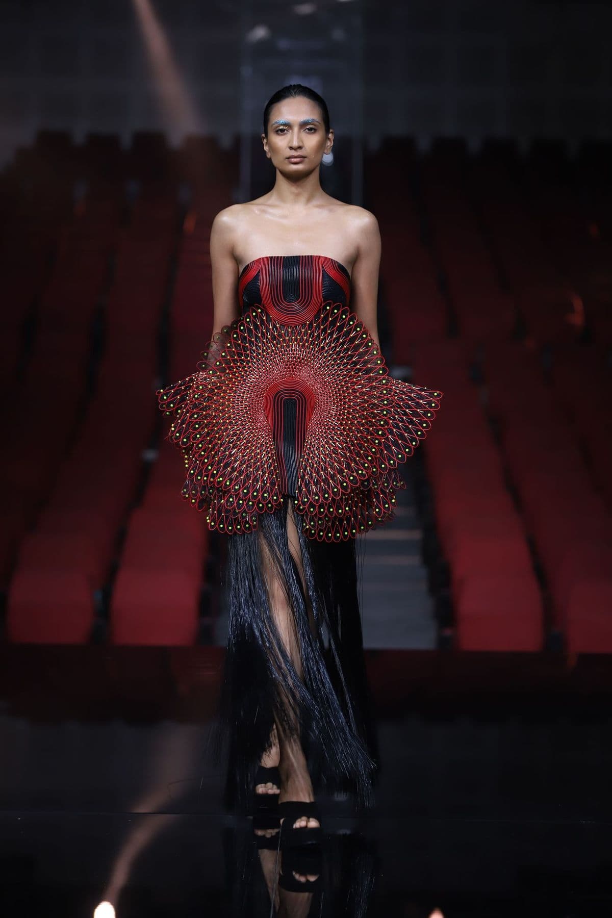 Model on a catwalk in a sculptural red and black gown